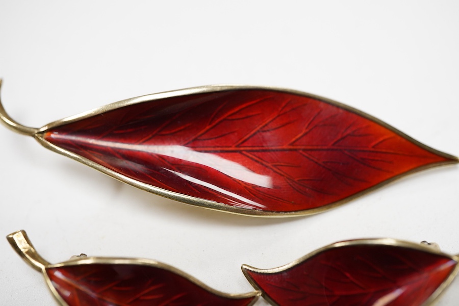 A Norwegian gilt white metal and red enamel demi parure, by David Andersen, comprising a leaf shaped brooch, 65mm and a pair of matching ear clips.